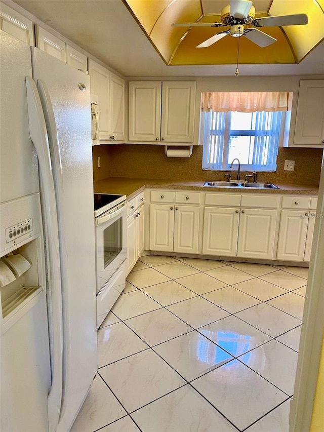 kitchen featuring tasteful backsplash, white appliances, sink, light tile patterned floors, and white cabinets