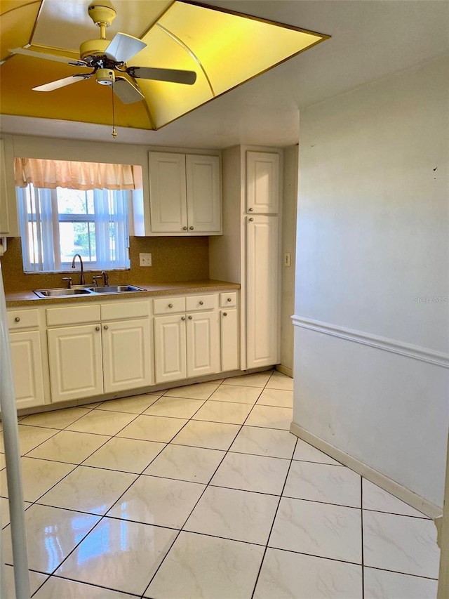 kitchen featuring tasteful backsplash, white cabinetry, ceiling fan, and sink