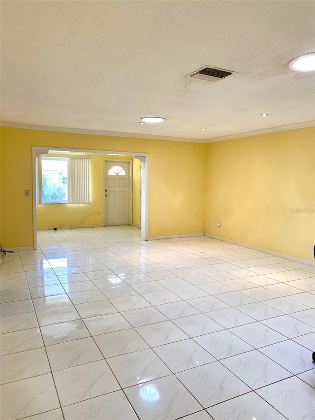 empty room with ornamental molding and a textured ceiling