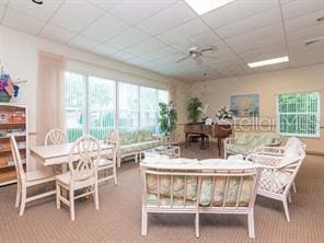 living room featuring carpet floors, ceiling fan, and a paneled ceiling