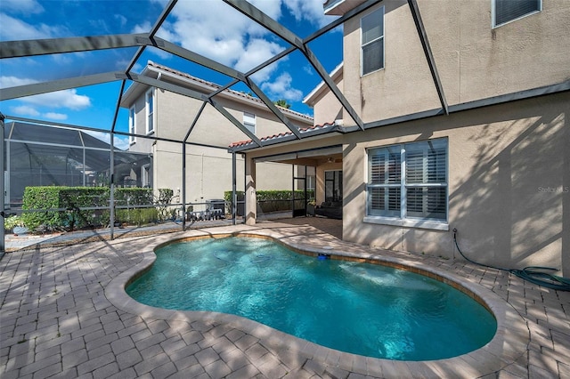 view of pool featuring glass enclosure and a patio area