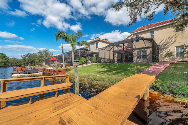 view of dock with a lawn, glass enclosure, and a water view