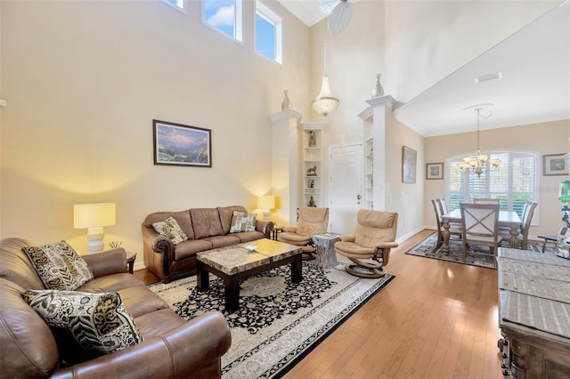 living room with a chandelier, a towering ceiling, hardwood / wood-style flooring, and decorative columns