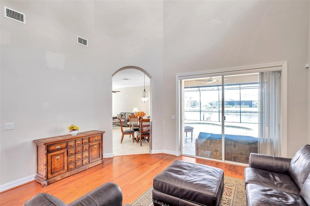 living room featuring hardwood / wood-style floors, a towering ceiling, and ceiling fan