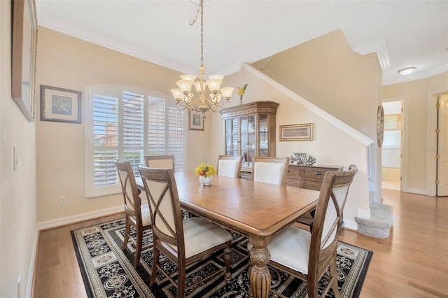 dining space with ornamental molding, a notable chandelier, and light wood-type flooring