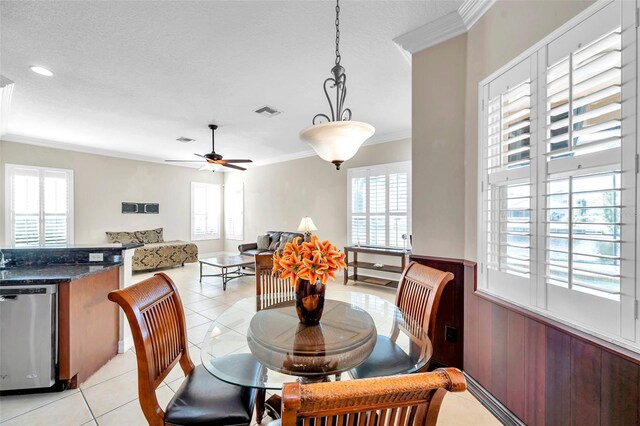 tiled dining area featuring ceiling fan, a textured ceiling, and ornamental molding