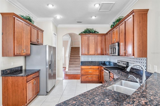 kitchen featuring dark stone counters, sink, stainless steel appliances, and ornamental molding