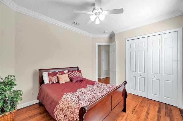 bedroom with ceiling fan, a closet, wood-type flooring, and ornamental molding