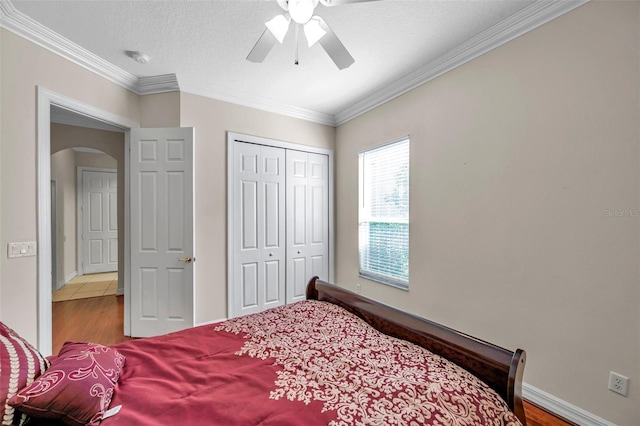 bedroom with hardwood / wood-style floors, ceiling fan, crown molding, and a closet