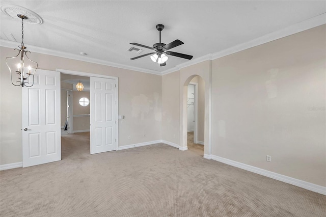 carpeted empty room featuring ceiling fan with notable chandelier and crown molding