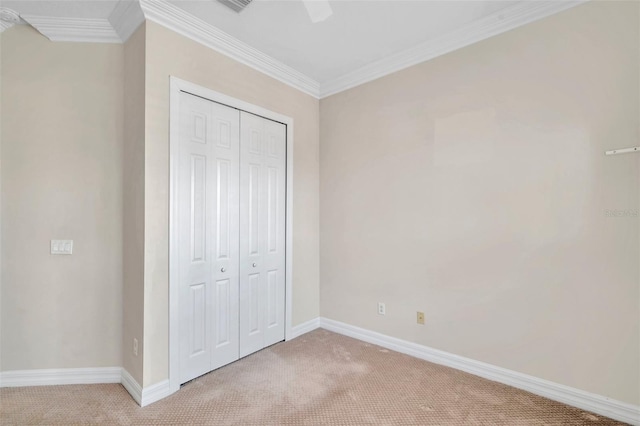 unfurnished bedroom with ceiling fan, light colored carpet, ornamental molding, and a closet