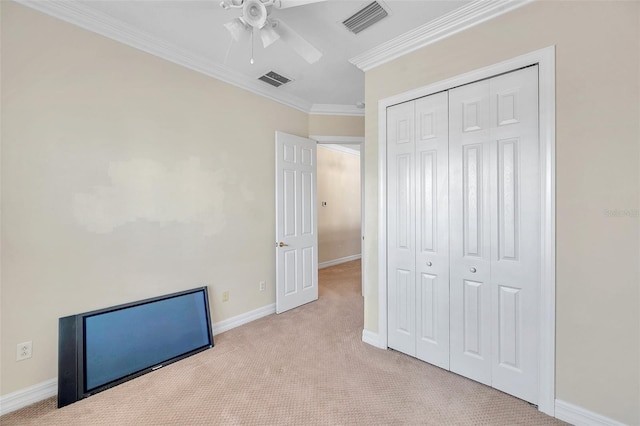 unfurnished bedroom with ceiling fan, crown molding, light carpet, and a closet