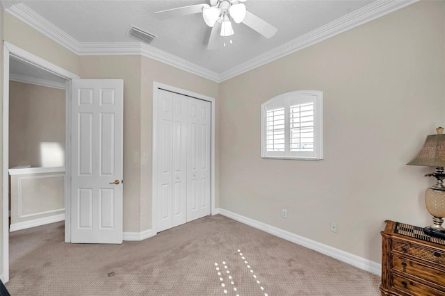 carpeted bedroom with ceiling fan, ornamental molding, and a closet