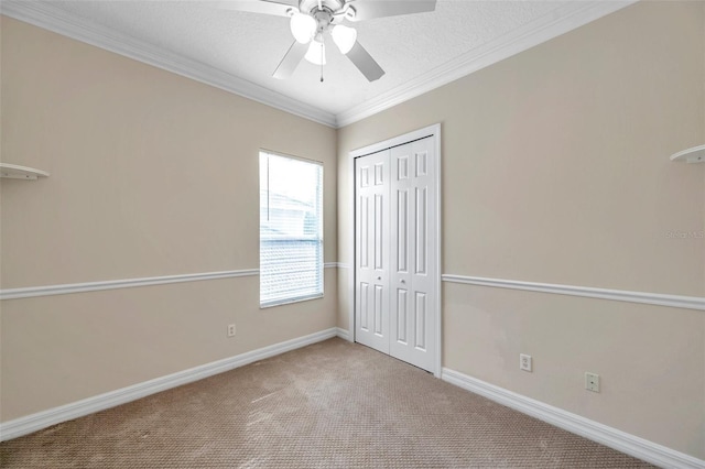 unfurnished bedroom featuring carpet flooring, a textured ceiling, ceiling fan, crown molding, and a closet