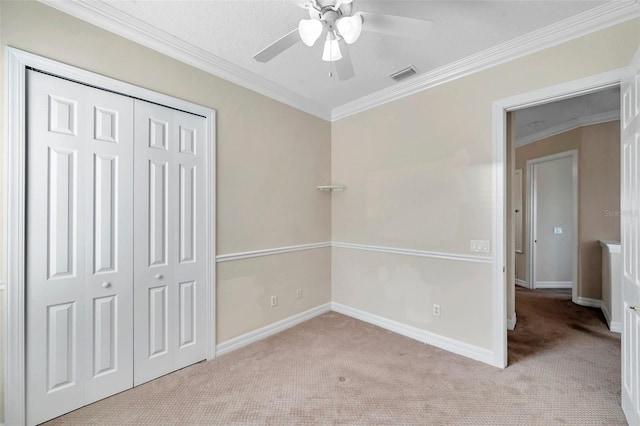 unfurnished bedroom featuring crown molding, ceiling fan, a closet, and light carpet