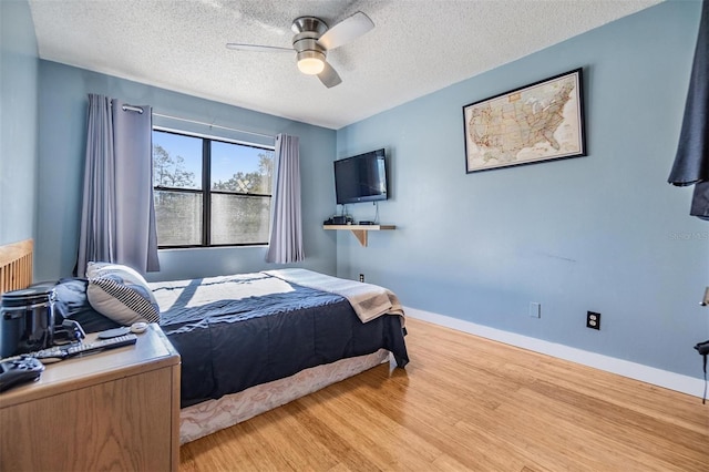 bedroom with a textured ceiling, light hardwood / wood-style flooring, and ceiling fan