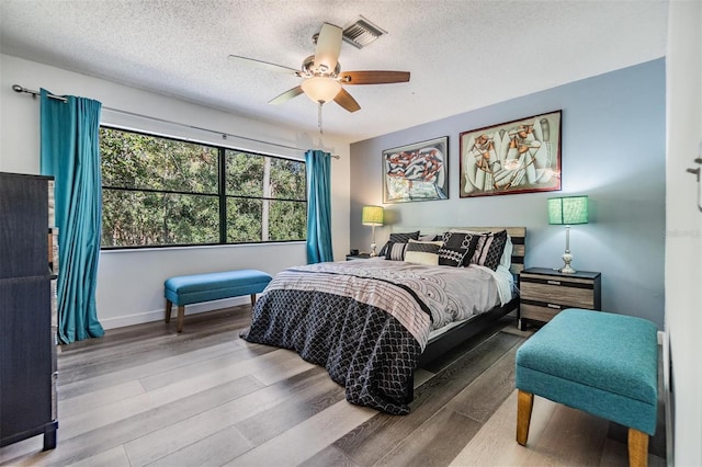 bedroom with ceiling fan, a textured ceiling, and hardwood / wood-style flooring