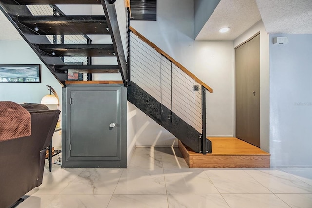 stairway featuring a textured ceiling