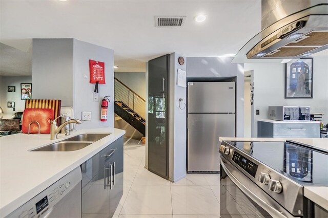 kitchen featuring sink, light tile patterned floors, island exhaust hood, and appliances with stainless steel finishes