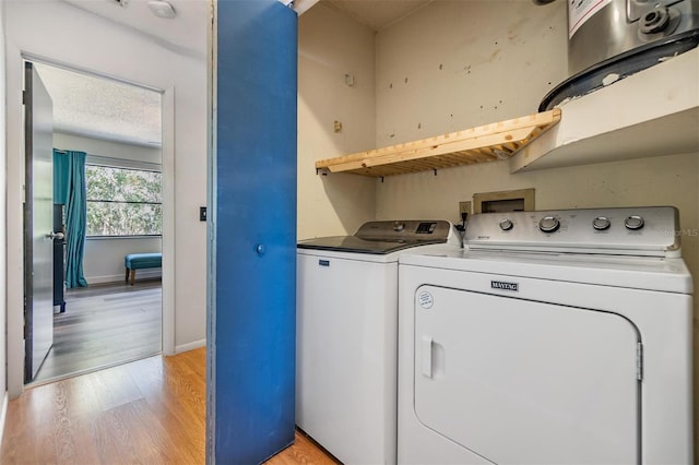 laundry area with washing machine and dryer, a textured ceiling, and light hardwood / wood-style flooring