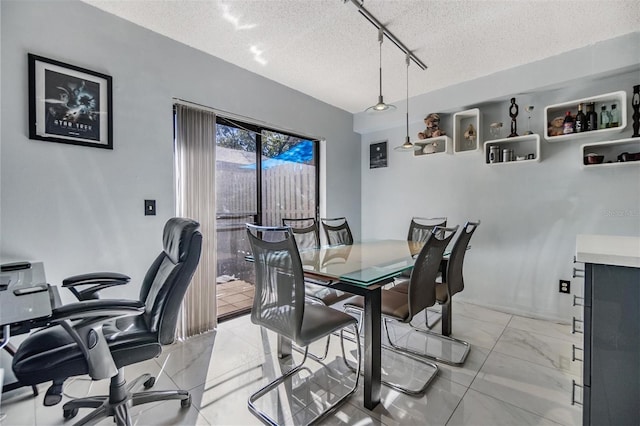 dining room with rail lighting and a textured ceiling