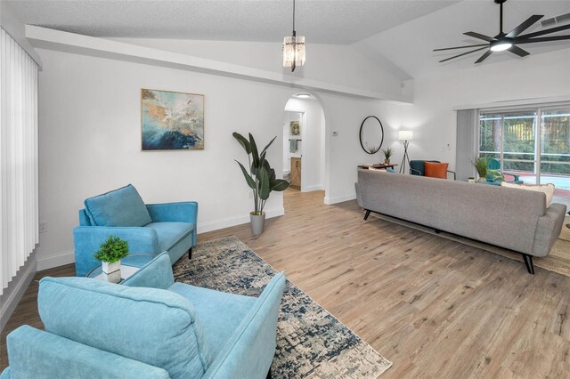 living room featuring ceiling fan with notable chandelier, lofted ceiling, and light wood-type flooring