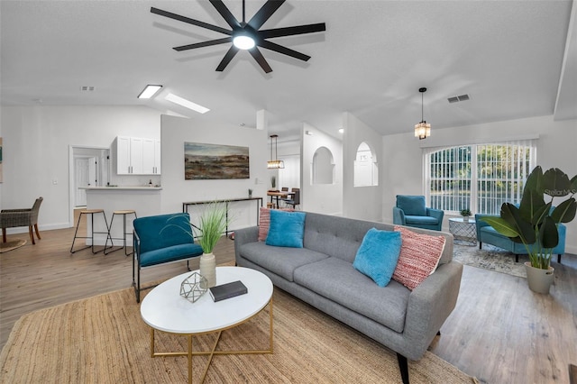 living room with ceiling fan, light hardwood / wood-style floors, and lofted ceiling