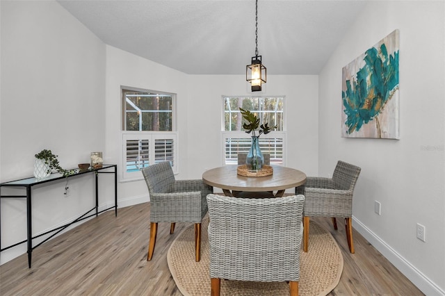 dining area with vaulted ceiling and light wood-type flooring