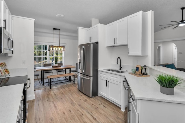 kitchen with white cabinets, light wood-type flooring, and appliances with stainless steel finishes