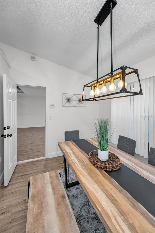 dining space with hardwood / wood-style flooring and a textured ceiling