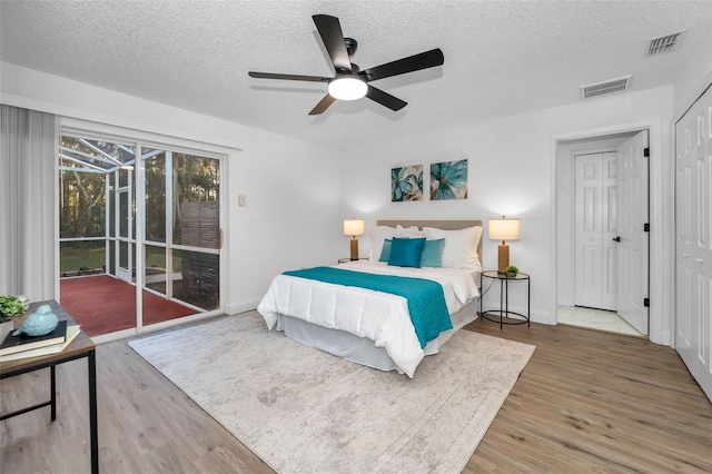 bedroom featuring ceiling fan, hardwood / wood-style floors, and a textured ceiling