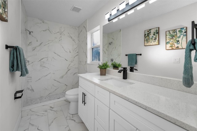 bathroom with a textured ceiling, vanity, toilet, and tiled shower