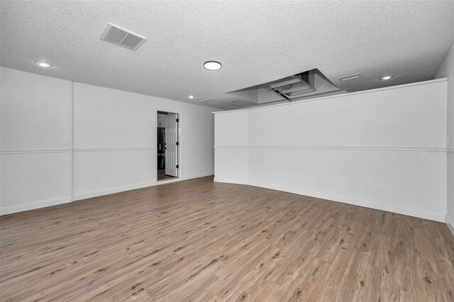 spare room featuring a textured ceiling and light wood-type flooring