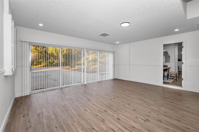 spare room with a textured ceiling and hardwood / wood-style flooring