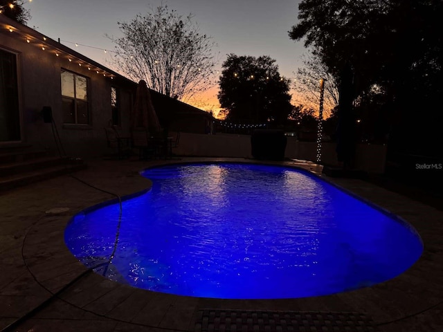 pool at dusk with a patio