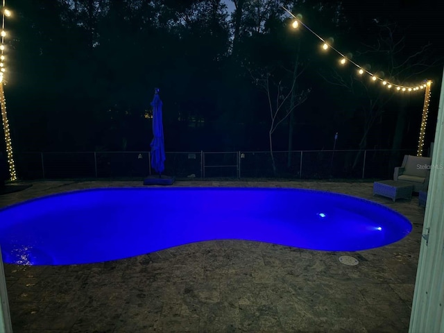 pool at twilight with a patio area