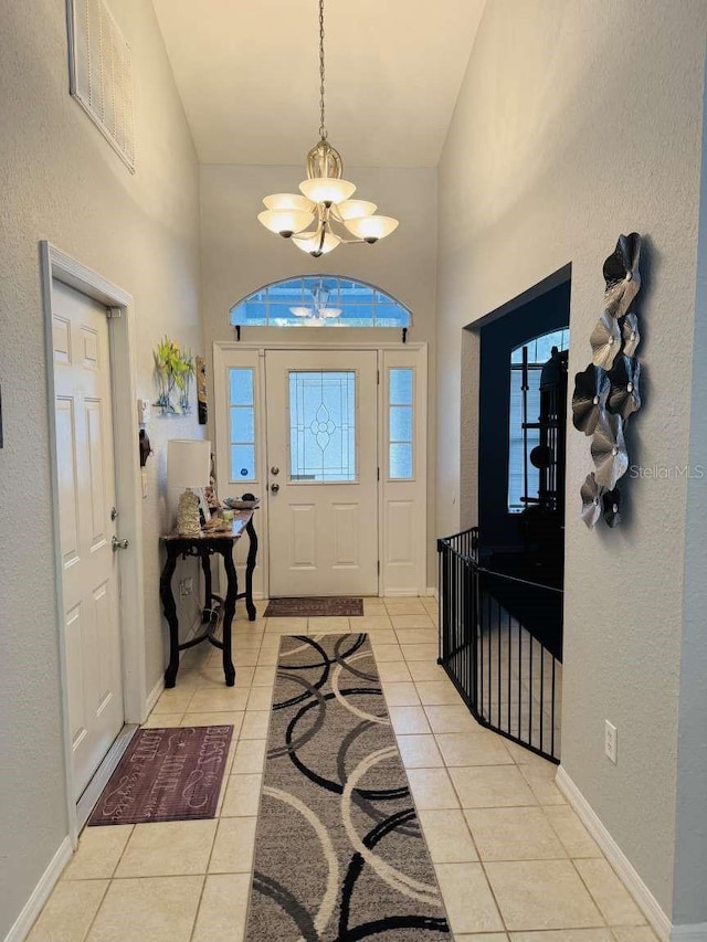 foyer entrance featuring plenty of natural light, light tile patterned floors, high vaulted ceiling, and a chandelier