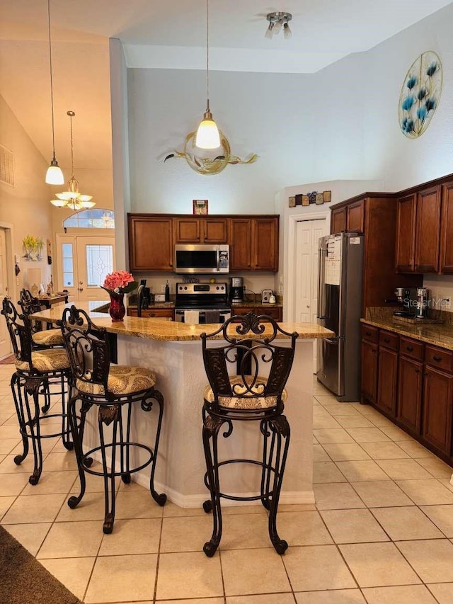 kitchen with appliances with stainless steel finishes, light tile patterned floors, a kitchen breakfast bar, and dark stone countertops