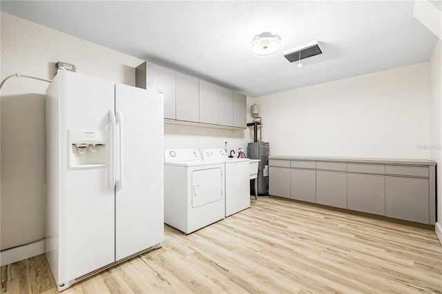 laundry room featuring cabinets, washer and dryer, light wood-type flooring, a textured ceiling, and water heater