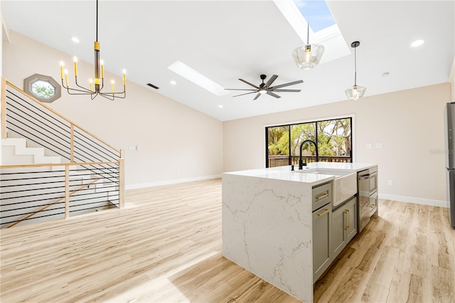 kitchen with sink, pendant lighting, light hardwood / wood-style floors, gray cabinets, and ceiling fan with notable chandelier