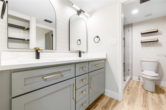 bathroom featuring vanity, hardwood / wood-style flooring, toilet, and a shower with shower door