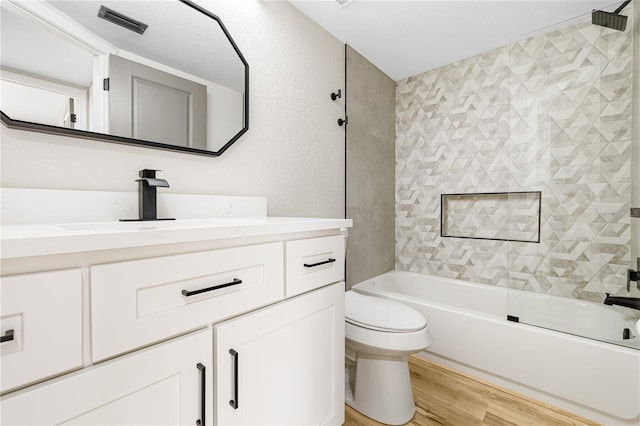 full bathroom with toilet, vanity, wood-type flooring, and tiled shower / bath