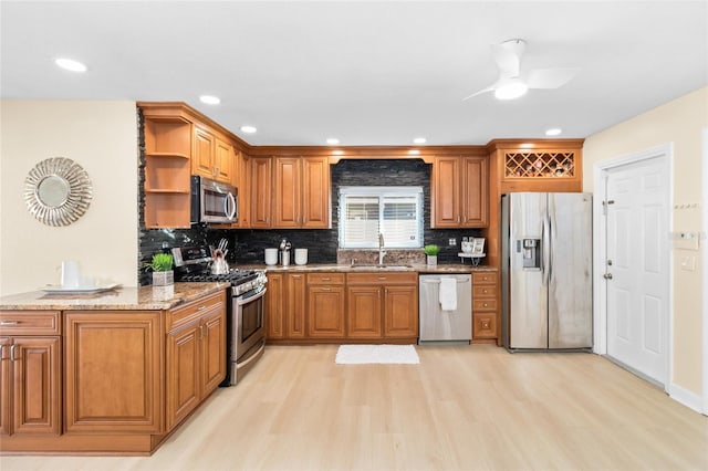 kitchen featuring appliances with stainless steel finishes, backsplash, ceiling fan, sink, and light hardwood / wood-style floors