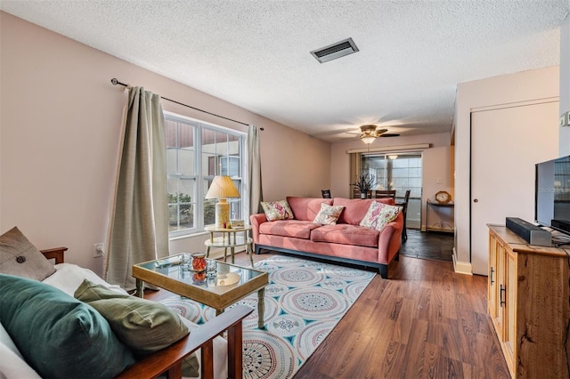 living room with ceiling fan, dark hardwood / wood-style flooring, and a textured ceiling