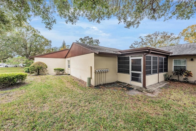 view of property exterior with a sunroom and a lawn