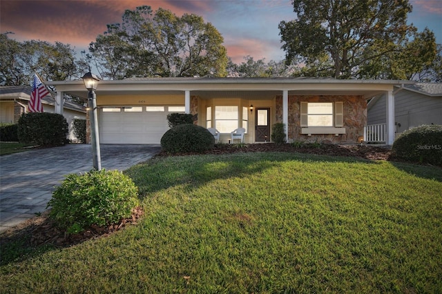 ranch-style house with a porch, a garage, and a yard