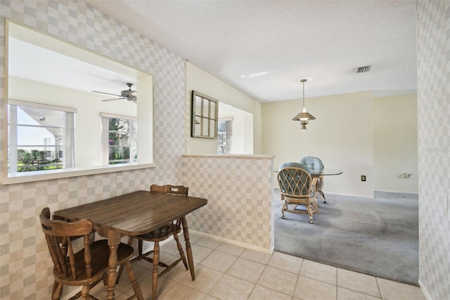 carpeted dining space with a textured ceiling and ceiling fan