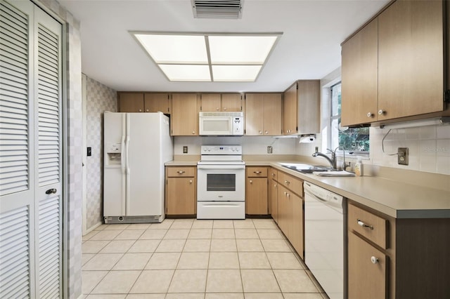 kitchen featuring white appliances, sink, and light tile patterned floors