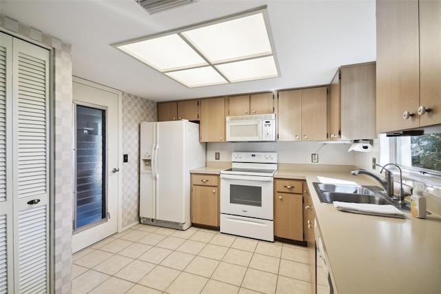 kitchen with light tile patterned flooring, white appliances, and sink