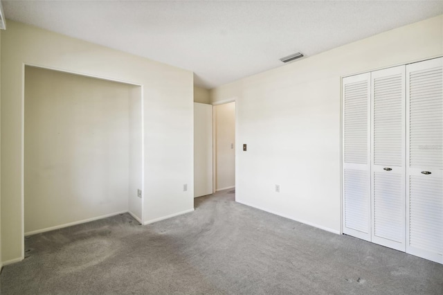 unfurnished bedroom featuring a closet and dark carpet